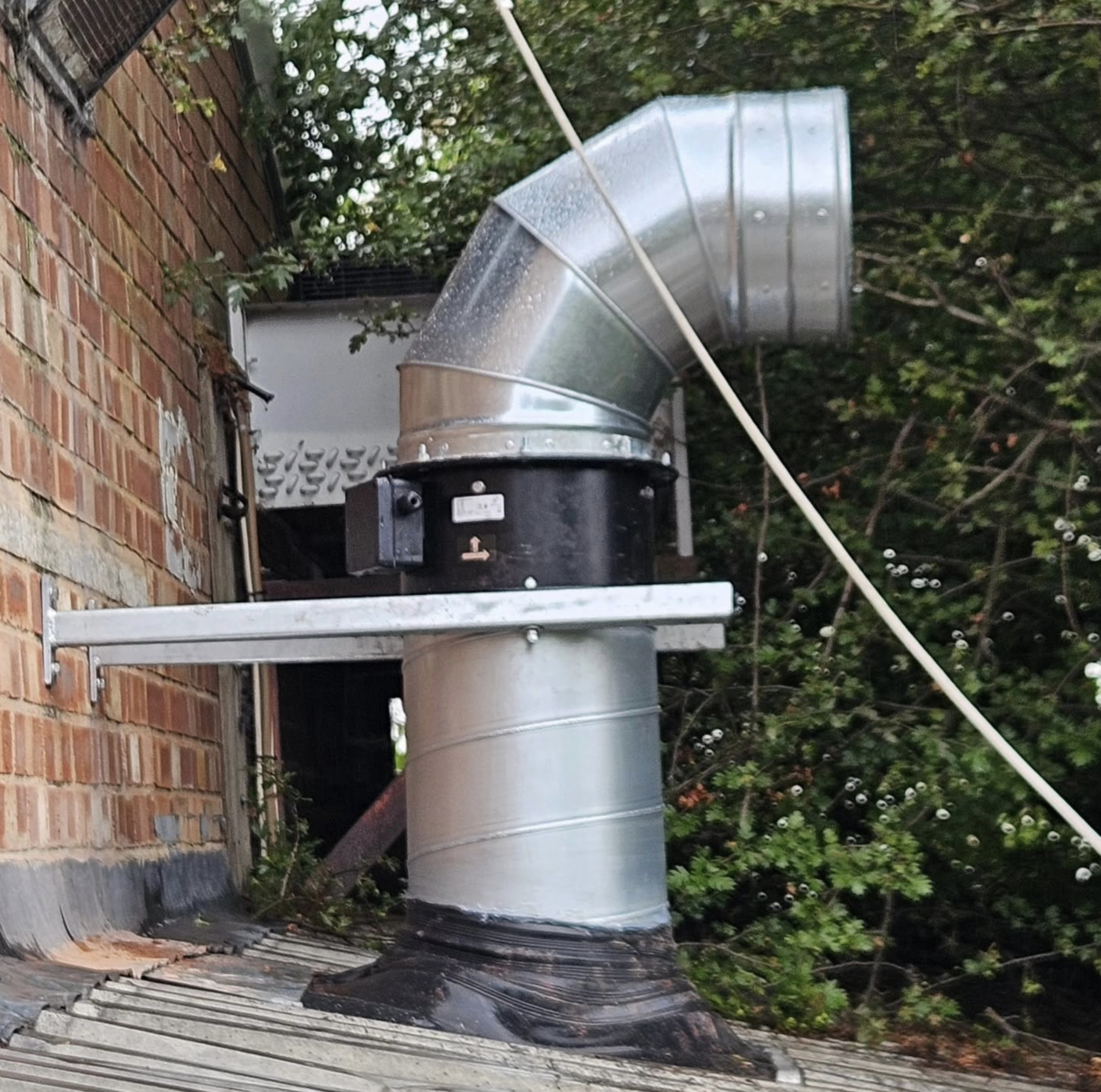External commercial extraction fan and ductwork beside a brick building