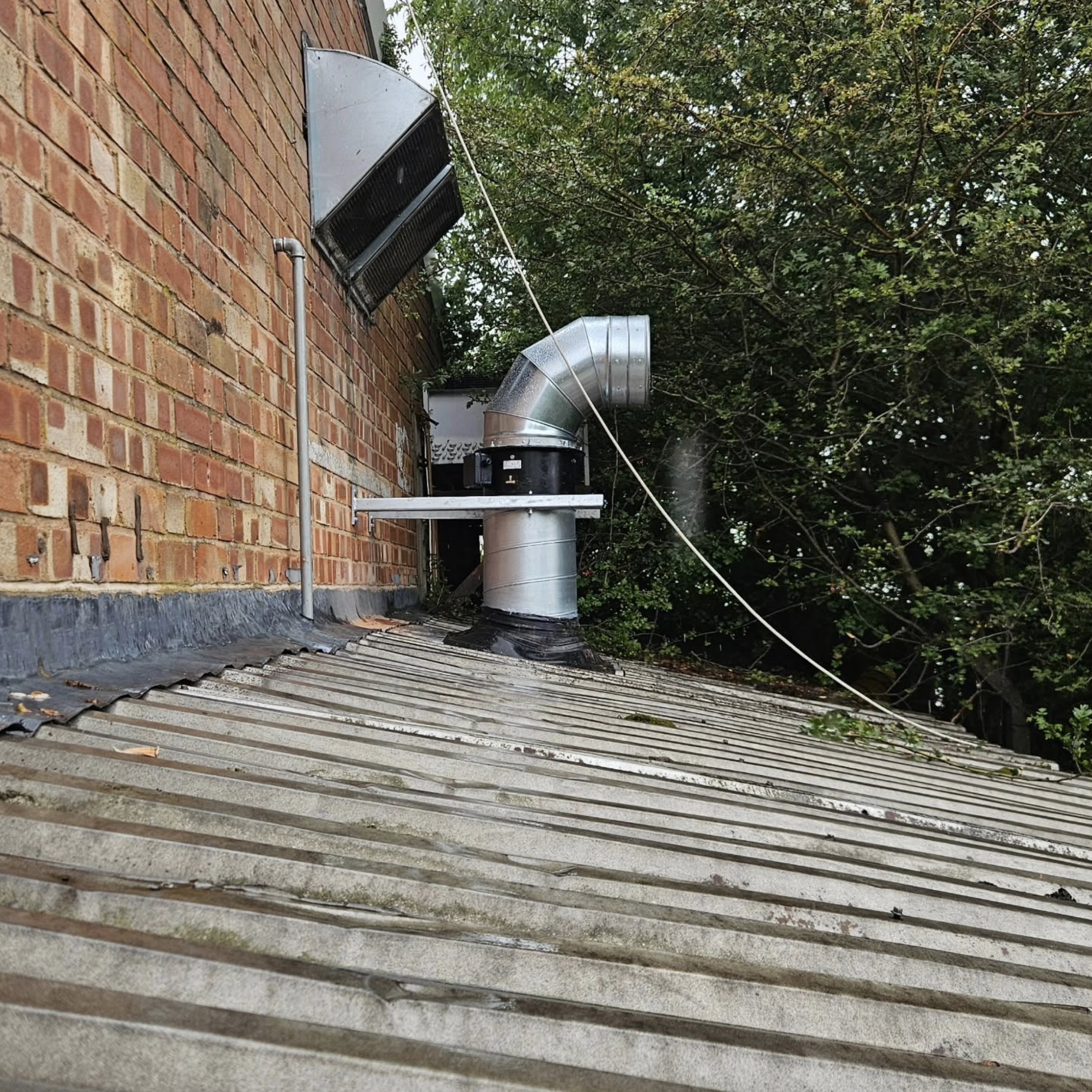 External roof ductwork and fan beside a brick commercial building
